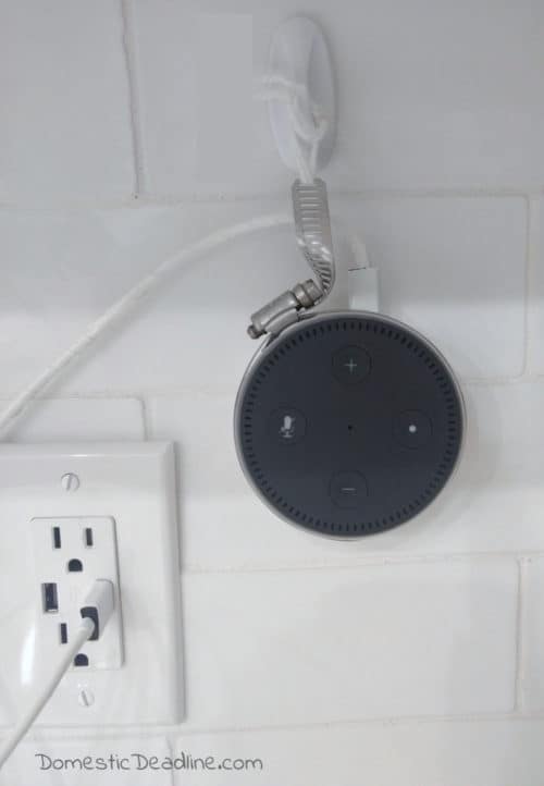 An easy and inexpensive way to hang your Amazon Alexa Dot on the wall near the outlet. This DIY Alexa Dot Holder uses a hose clamp and command hooks. Upcycle Challenge www.domesticdeadline.com