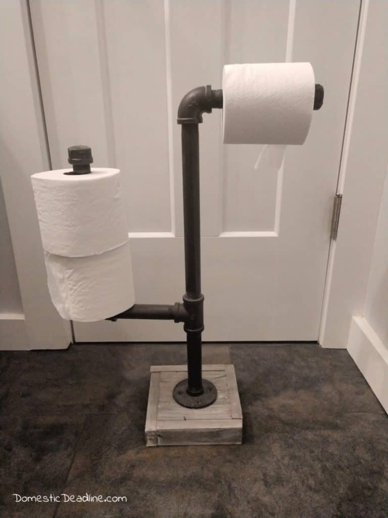 Learn how to use industrial gas pipe to make a toilet paper holder to dispense and hold extra rolls. Perfect for industrial farmhouse decor! DomesticDeadline.com
